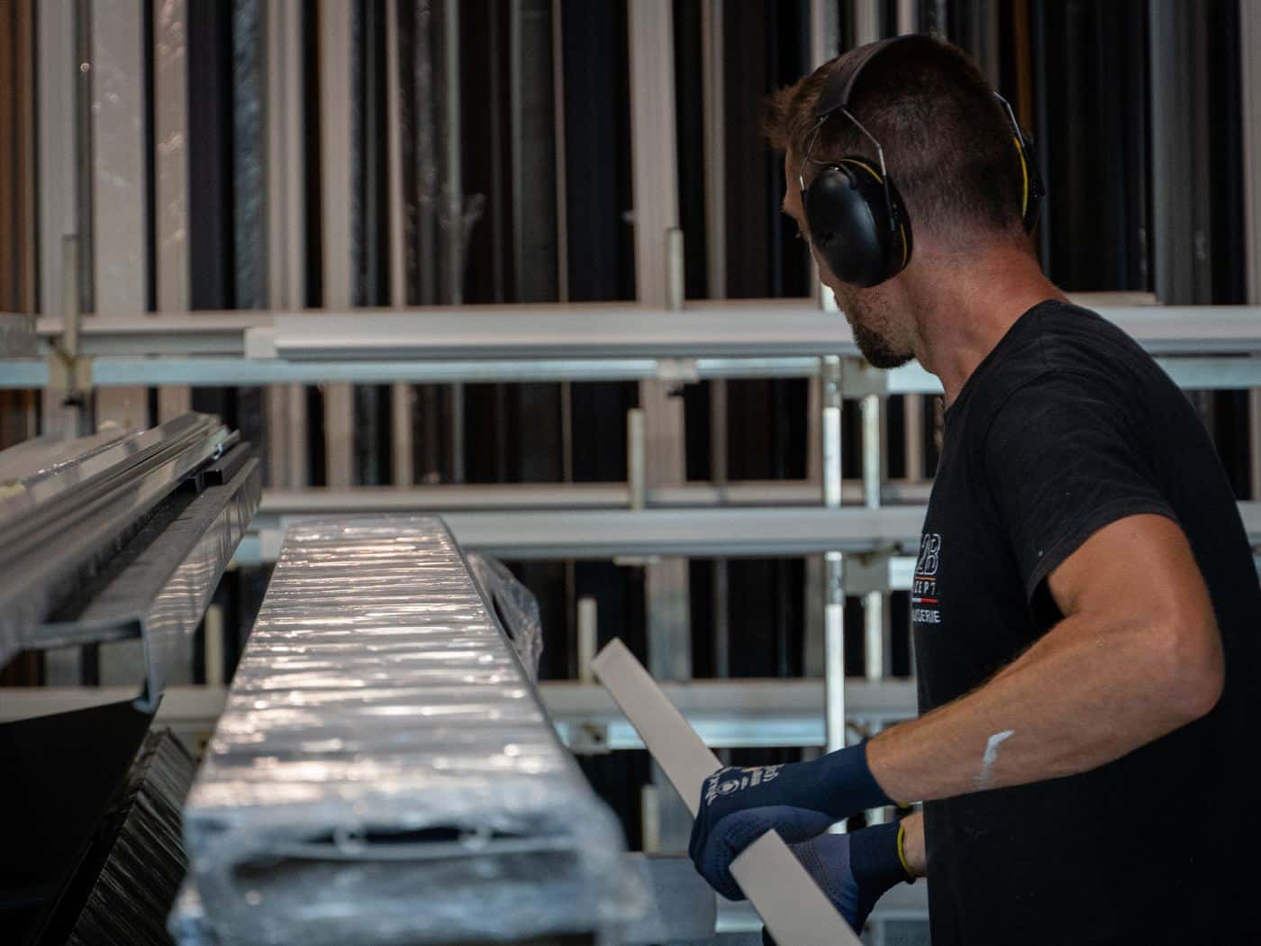 Menuisier A2B Concept sélectionnant des profilés aluminium dans le stock de l'atelier